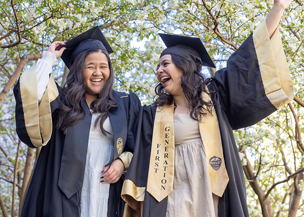 women raising hands and smiling after graduating