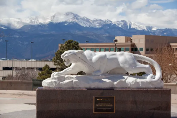 A mountain lion statue in front of the rocky mountains