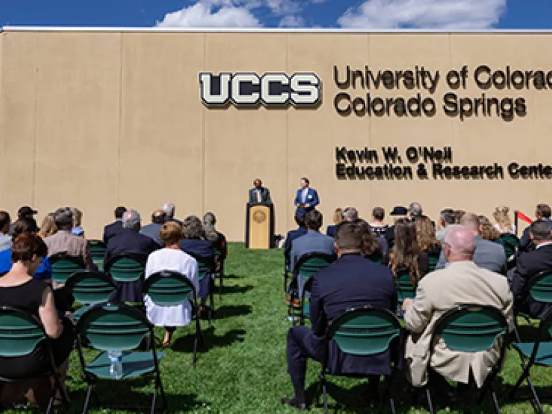 A group of people are seated before the UCCS cybersecurity center