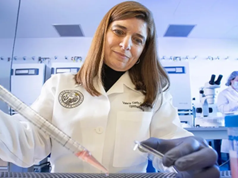 A woman scientist wearing a lab coat working with a pipette